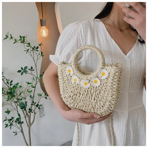 Detailed macro view of beige woven straw handbag with handmade white daisy crochet flowers