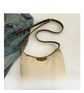 Detail view of the nylon shoulder bag with brown leather trim and adjustable strap