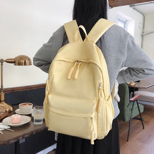 Close-up of yellow nylon backpack with braided rope zipper details in a cozy cafe