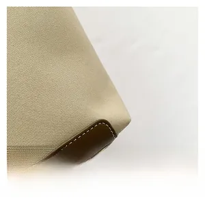 Macro shot of khaki canvas fabric with brown leather trim and white stitching detail