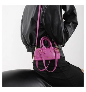 Detail of a bright purple mini leather dome bag with slim strap on black leather jacket