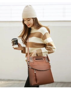 Close-up of brown leather bag with silver studs and star pendant on female model