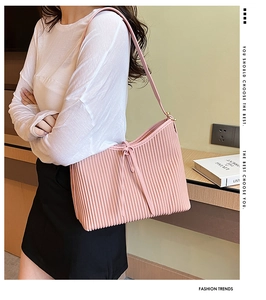 Detail of pink pleated tote bag with slim shoulder straps shown on a model