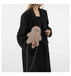 Lebkuchenmann Umhängetasche mit goldener Kette auf schwarzem Oversize-Blazer
