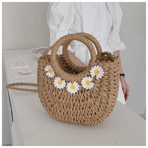 Detail view of handmade woven straw bag with white daisy appliques and dual handles