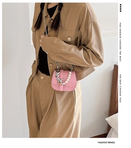Mini sac bandoulière rose en cuir avec chaîne en perles et cœur argenté porté par mannequin
