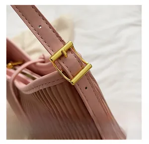 Detail shot of golden metal buckle and pleated pink PU leather texture on trendy handbag
