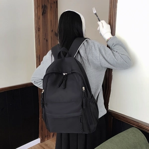 Close-up of black nylon backpack featuring durable woven rope zipper pull and spacious front pocket