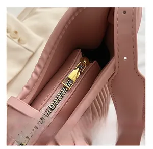 Detailed close-up of smooth gold metal zipper and pink pleated leather on fashion handbag