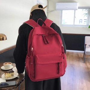 Rear view of a red nylon backpack with adjustable straps in a casual cafe setting
