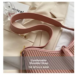 Close-up of pink pleated PU leather handbag with wide shoulder strap and gold hardware