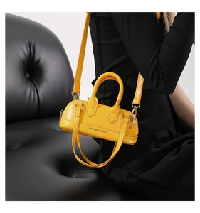 Close-up of bright yellow PU leather crossbody bag with fashion slogan and gold buckles