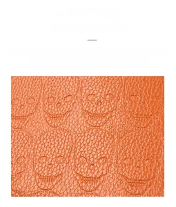 Gros plan sur le cuir ciré orange avec texture litchi et détails de crânes embossés