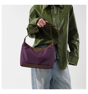 Detail of purple nylon shoulder bag with leather trim on model wearing a green shirt