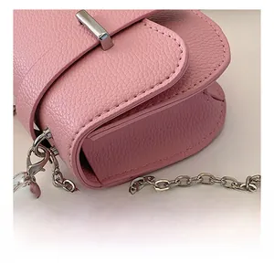 Détail du sac en cuir grainé rose avec pendentif cœur argenté et chaîne en métal
