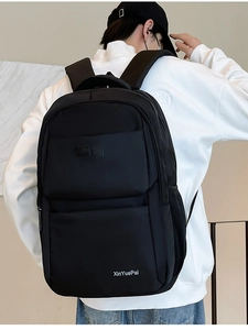Detailed view of black nylon backpack on male model showing side pocket and back straps