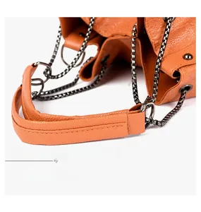 Gros plan détaillé du sac à main orange en cuir grainé avec chaîne en métal gris foncé