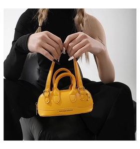 Detail of yellow PU leather mini handbag with top handles and fashion text logo