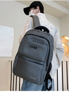 Detail view of the dark grey nylon backpack featuring multi-layer zip pockets and side mesh bag