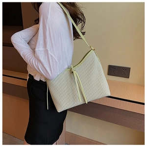 Detail of a creamy beige pleated PU leather shoulder bag with drawstring closure