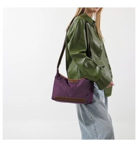 Detail view of purple nylon shoulder bag with brown leather trim worn by model