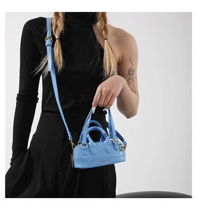 Detail of light blue PU leather mini Boston bag with gold zippers and fashion lettering