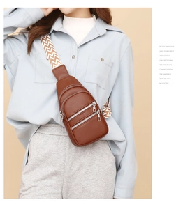 Detail of brown leather chest bag with three zip layers and a chevron pattern strap