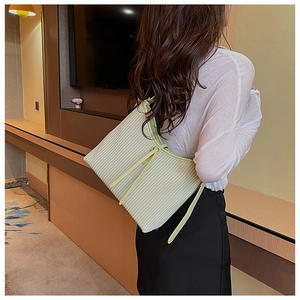 Close-up of light green pleated handbag with vertical accordion texture and slim strap