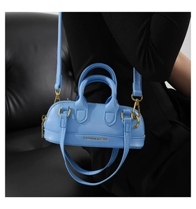Detail of a mini bright blue PU leather bowling bag with golden hardware and fashion logo