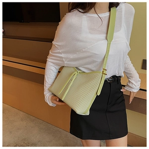 Detail of mint green crossbody bag featuring vertical pleated texture and wide strap