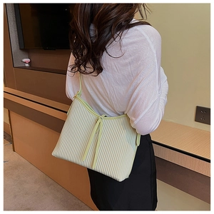 Detail of light green pleated handbag showing vertical texture and knot design on the strap