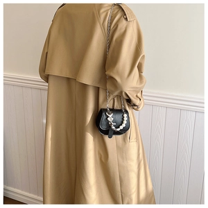 Détail du sac de selle en cuir noir avec chaîne décorative à perles et pendentif cœur argent