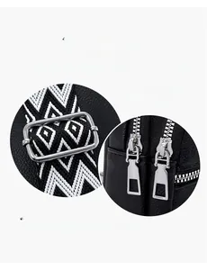 Detail of silver buckles, double zippers, and woven strap on black pebble leather bag