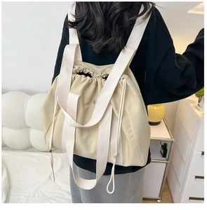 Beige nylon drawstring tote backpack shown in use with wide woven cotton straps