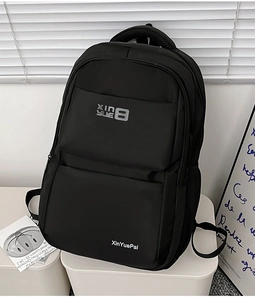 Detail shot of black nylon backpack showing XinYuePai branding and side mesh pocket