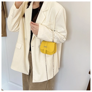 Détail d'un sac à main jaune en PU avec anse en perles et chaîne porté par un mannequin
