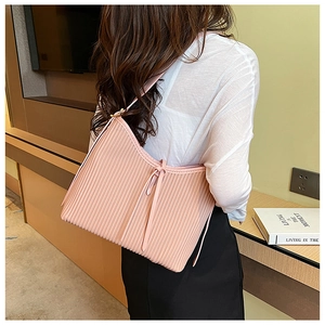 Detail of a pink PU leather handbag with elegant vertical pleats and decorative side ties