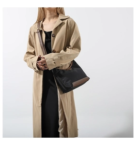 Detail of a nylon crossbody bag in black and brown worn with a stylish trench coat
