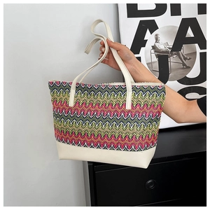 Detail of colorful woven wave pattern on tote bag with cream leather strap and base