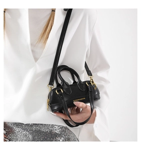 Detailed macro shot of a black mini PU leather handbag with golden zipper and logo
