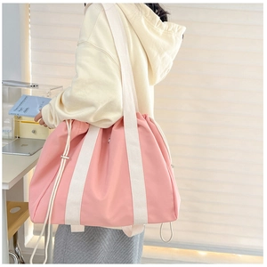 Pink drawstring tote bag in high-density nylon fabric shown on a female model's shoulder