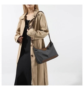 Detail of black nylon hobo bag with brown leather trim and embossed brand logo on the side