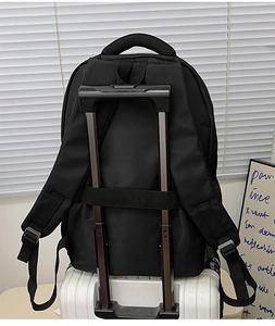 Detail showing the trolley sleeve of a black nylon backpack attached to a luggage handle
