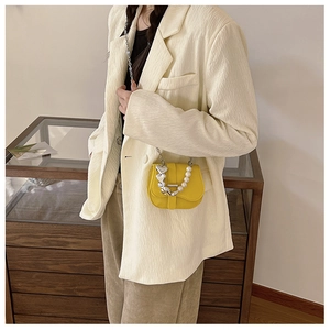 Détail du mini sac bandoulière jaune avec chaîne en perles blanches et cœurs en argent