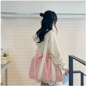 Detailed view of pink drawstring tote bag featuring wide white shoulder straps and fabric texture