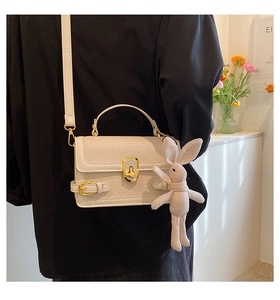 Détail du sac en cuir PU blanc à grain avec fermoir doré et breloque lapin en tricot