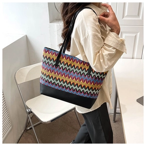 Detail shot of multi-colored woven texture and black synthetic leather strap on tote bag