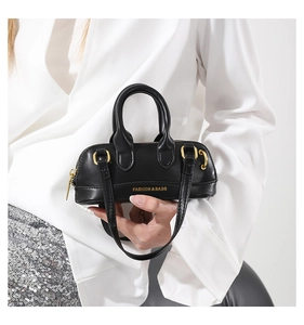 Close-up of black mini PU leather boston bag with golden fashion & bags logo hardware