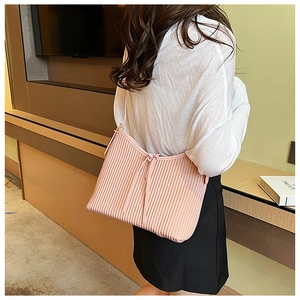 Detail of light pink pleated PU shoulder bag with drawstring detail on a model