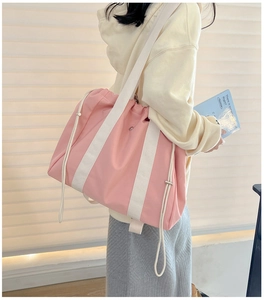 Detailed side view of large pink nylon tote bag with drawstring and white woven straps